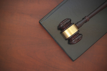 Wooden judge gavel and legal book on wooden table