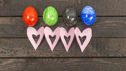 colorful raw eggs and pink heart cards on brown wooden backgound