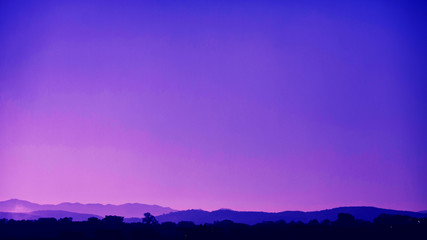 Silhouettes of the mountain hills at purple sunset. Mountain cascade background