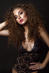 Beauty woman portrait on black background with curly hair in sexy underwear. 