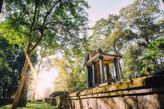 statue of buddha in old pavilion in ancient public garden with sunflare for background in cambodia