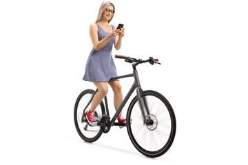 Young woman using a phone and riding a bike