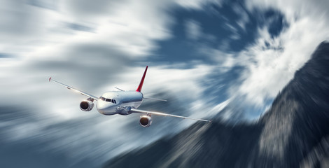 Passenger aircraft in motion. Modern airplane mith motion blur effect at sunny bright day. Landscape with passenger airplane, blurred clouds, mountains, blue sky. Business travel. Commercial plane © den-belitsky