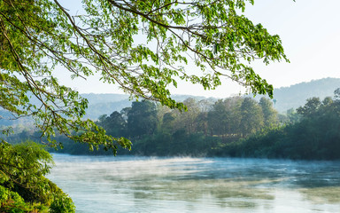 Beautiful cold river with steam on surface when sunshine in the morning time with golden light , there are leaf  in foreground