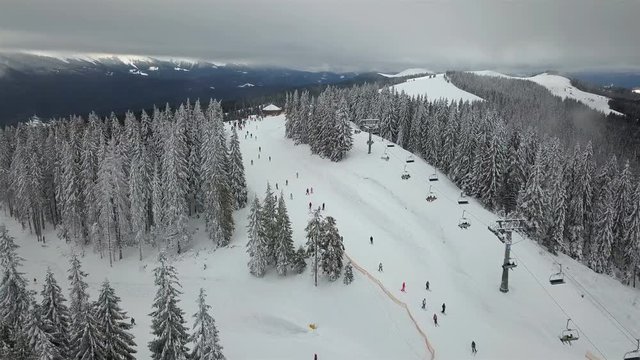 Skiers and snowboarders go down the slope in a ski resort  Bukovel, Ukraine. Top view 
