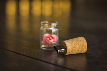 Fototapeta na wymiar Glass jar tied with a ribbon. Stopper USB flash drive, Original flash drive. Rose in a flask. Glass USB Flash Drive. Wedding flash drive as a gift.