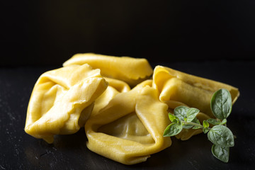 Uncooked ravioli stuffed with meat on a dark slate