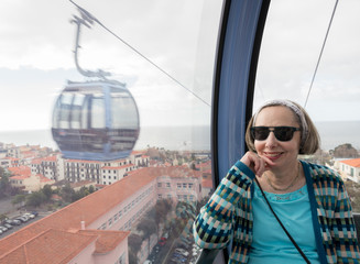 Senior adult woman riding in cable car over Funchal