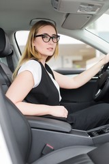 Girl with glasses sitting in the cabin of a new car