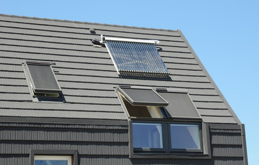 Modern attic roof with solar panels, skylights and blinds window for sun protection and house...