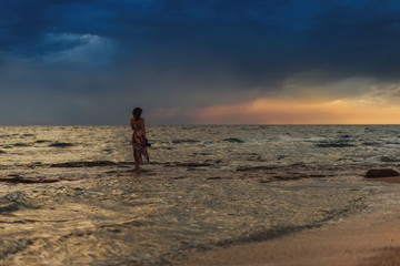 Female with camera in the sea near coast of the Greek island in stormy weather. It's raining on the horizon