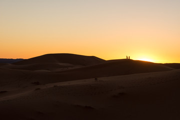Fototapeta na wymiar Tourists at sunset on the sand dunes
