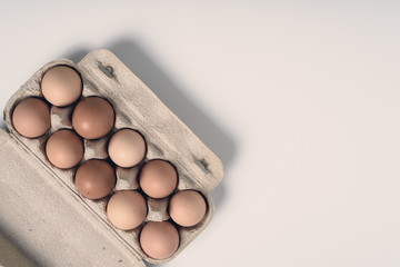 Flat image of rustic eggs in paper container on white background