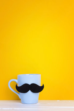 Blue mug with a mustache on yellow background. Copy space.