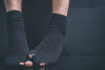 The feet of the poor debtor's in black holey socks on a black background