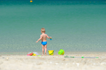 Two year old toddler playing on beach