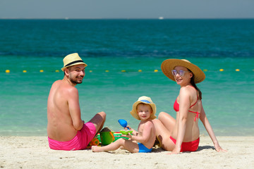 Family on beach. Toddler playing with mother and father.