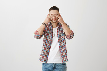 Cute tired caucasian student of university holding glasses in hand while rubbing eyes, being exhausted and overloaded with work, standing against gray background. Freelancer has bad sight cause job