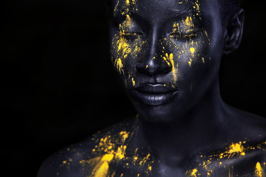 Cheerful young african woman with art fashion makeup. An amazing woman with black makeup and leaking yellow paint