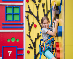 Little girl hanging on holds on climbing wall