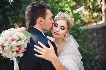 The groom gently kisses his beautiful bride. Young fashionable bride. Wedding.
