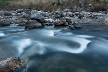 Naklejka na ściany i meble River water flowing through rocks at dawn