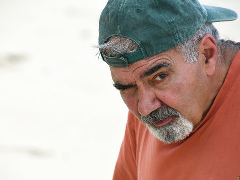 elderly Lebanese man with gray mustache and goatee wearing baseball cap backwards