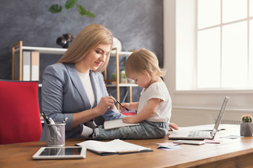 Young mother holding baby while writing notes