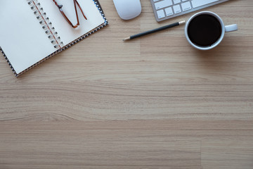 Office desk workplace with keyboard, notepad and glasses on wooden background. Top view with copy space