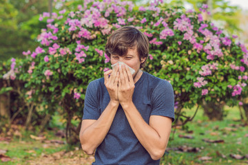 Young man sneezes because of an allergy to pollen