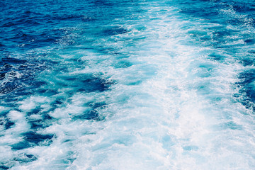 Obraz premium Waves, foam and wake in the ocean with blue water caused by cruise ship.