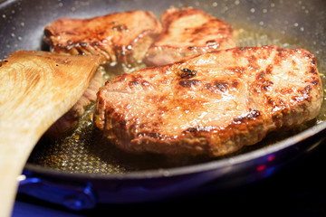 Close up of delicious steaks on frying pan ready to eat.