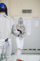Two teenager fencers fighting with rapiers on the fencing tournament
