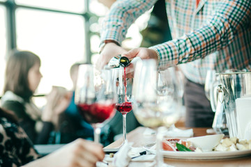 Sommelier pouring red wine in a glass at a restaurant table