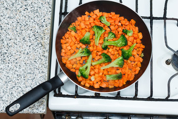 Fresh vegetables in a frying pan. Fresh vegetable products, freshly frozen odietic vegetables, broccoli, carrots are cooked in a frying pan on a gas stove.