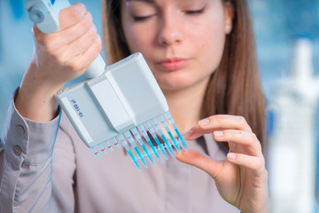 student woman with multi pipette and other PCR items in microbiological / genetic laboratory