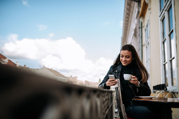 Young gorgeous woman relaxing on the terrace balcony looking at smartphone.