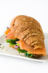 Croissant sandwich with salmon and vegetables isolated on white background
