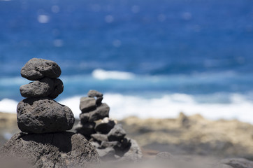 Fototapeta na wymiar Cairns on the coast. group of stacked stones in front of the blue ocean