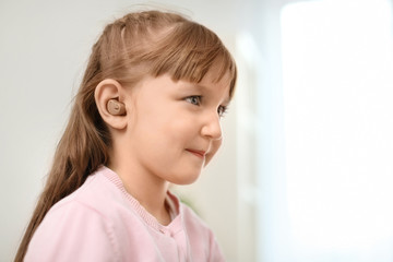 Little girl with hearing aid indoors