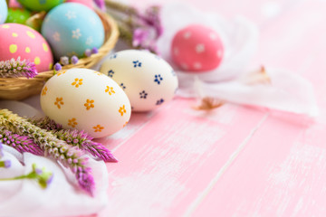 Happy easter! Colorful of Easter eggs in nest with paper star, flower and Feather on pastel color bright pink and white wooden background.