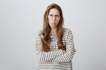 Childish girl expresses her dislike, being impolite and rude. Portrait of attractive displeased...