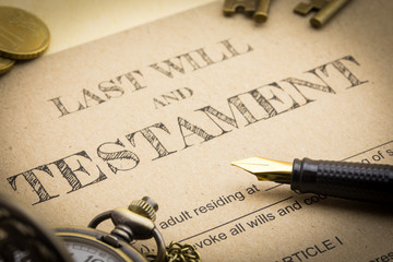 Close up view of Black pen, Gold coins, Keys and vintage clock on Last will and testament document...