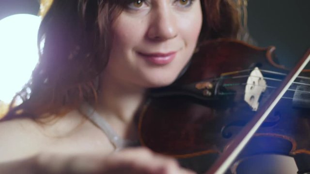 concert of live music, attractive woman playing on violin at evening event close-up