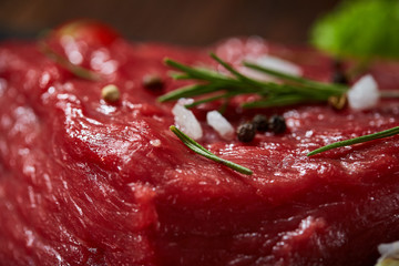 Composition of raw beefsteak on slate board with vegetables and seasoning, selective focus, close-up.