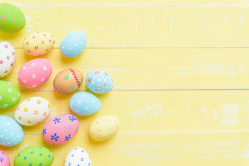 Happy easter! Colorful of Easter eggs on pastel color bright yellow and white wooden background.