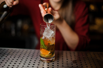 barmaid prepares a mojito in a crystal glass, adding white rum