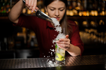 barmaid adds to mojito in a crystal glass crushed ice