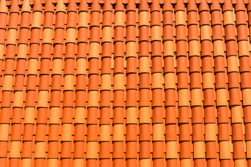 Red orange clay roof tiles in seamless diagonal pattern on sunny day, abstract background texture, architectural details,
