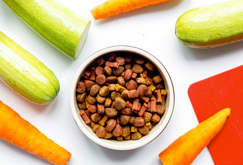 Dry dogfood with carrot and zucchini on table background top vie